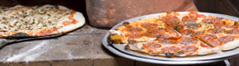 Brick oven pizza being pulled out of the oven
